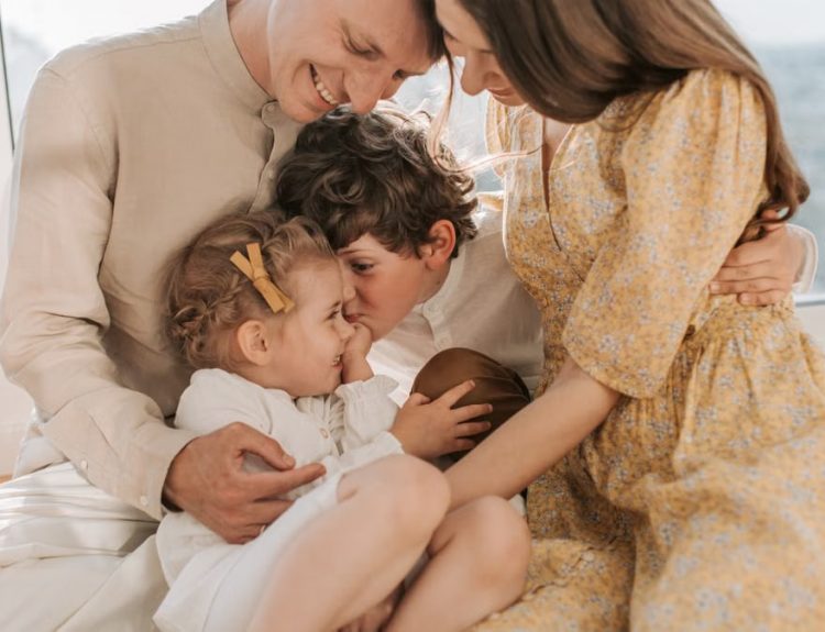 A happy family of four sitting together and sharing a loving moment indoors.