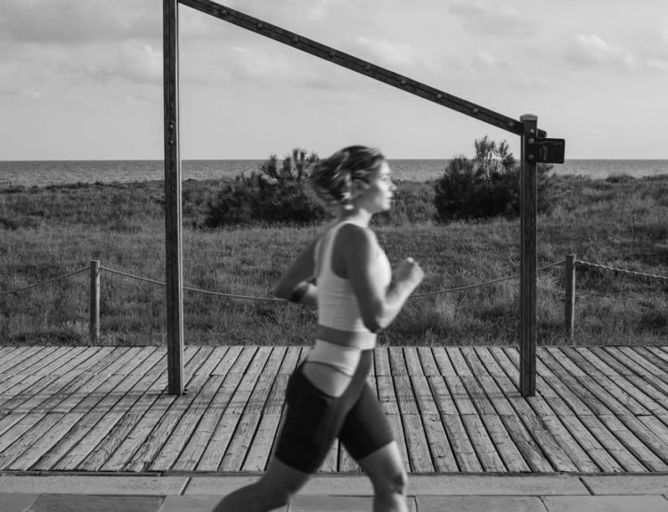 A woman jogs along a coastal boardwalk in Castelldefels, Spain, promoting fitness and outdoor exercise.